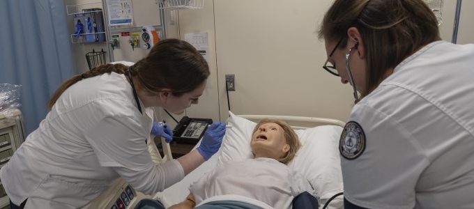 Two nursing students assessing the simulation manikin